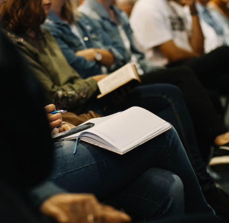 conference, someone seated with her phone and notebook open